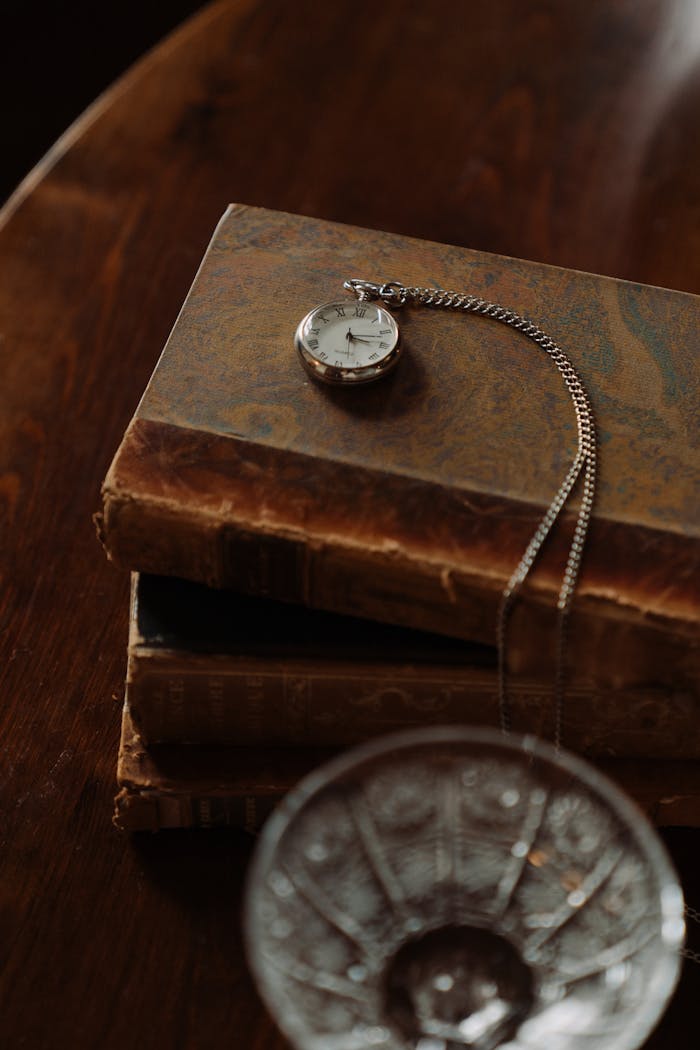 A silver pocket watch elegantly displayed on weathered books, capturing a timeless vintage aesthetic.